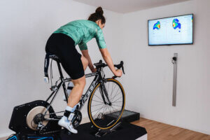 Radfahrerin bei der Druckmessung auf dem Rollentrainer, auf dem Monitor die Druckverteilung